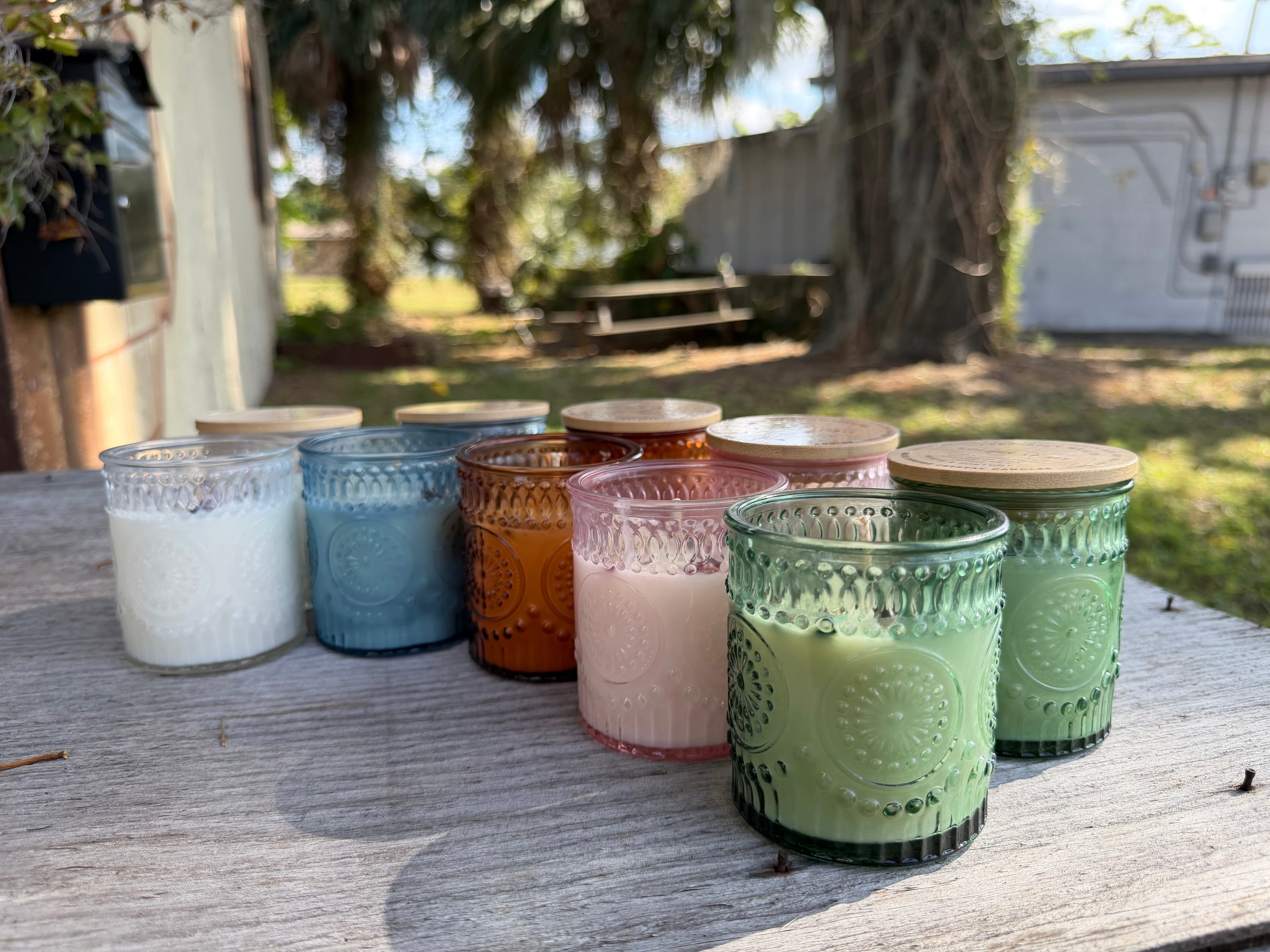 Set of colorful glass candles on a wooden surface outdoors
